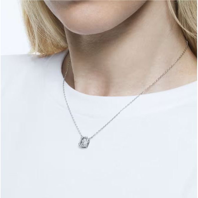 Woman wearing a silver necklace with a square pendant on a white shirt