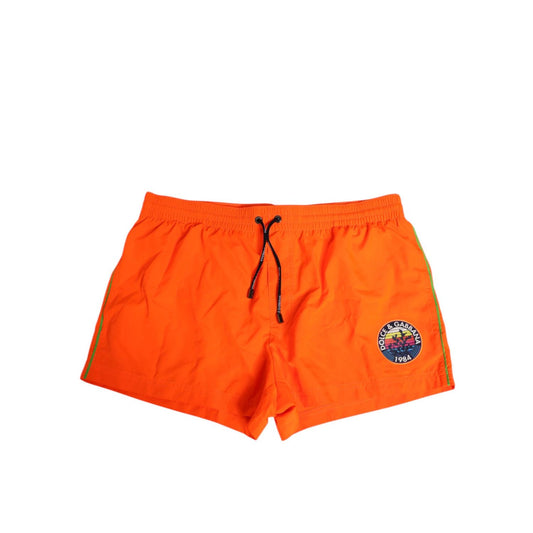 Dolce & Gabbana Orange Polyester Beachwear Men Shorts Swimwear with logo and drawstring waistband on white background.