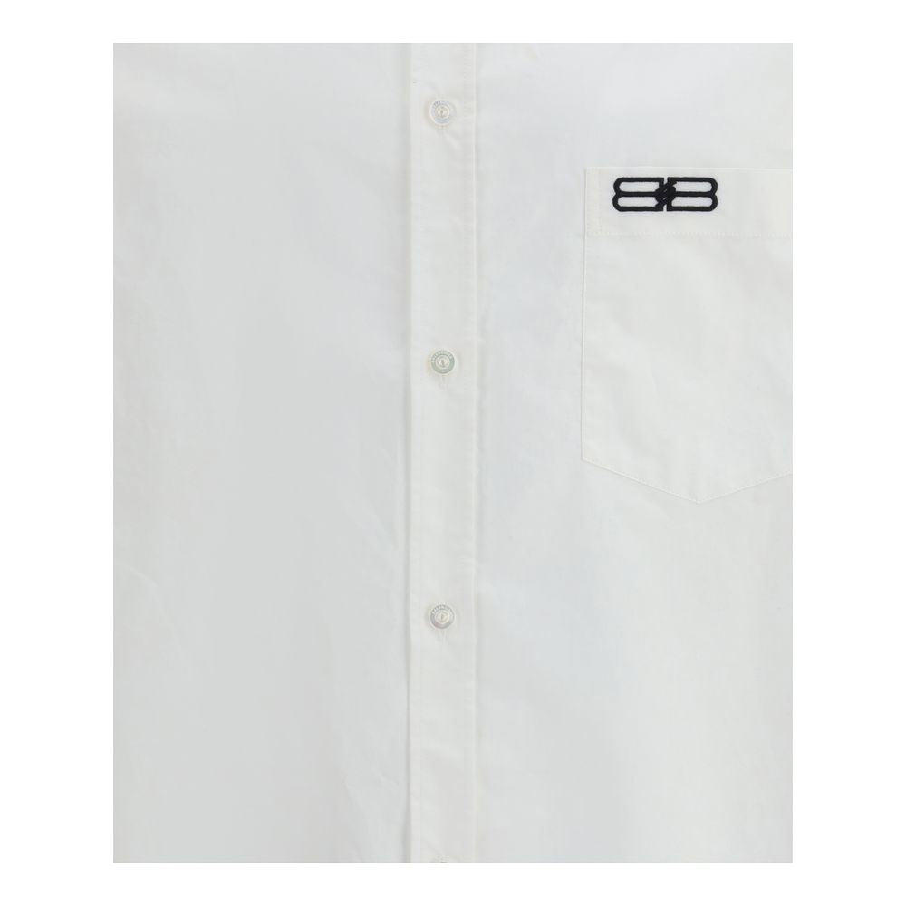 Balenciaga White Cotton Dress Shirt with embroidered logo, front button closure, and asymmetrical hem for a modern, oversized fit.