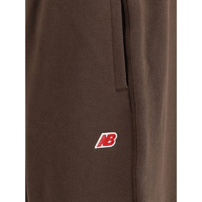 Close-up of New Balance Brown Cotton Joggers (Workout Pants) featuring logo patch and pocket detail with elasticated hem.