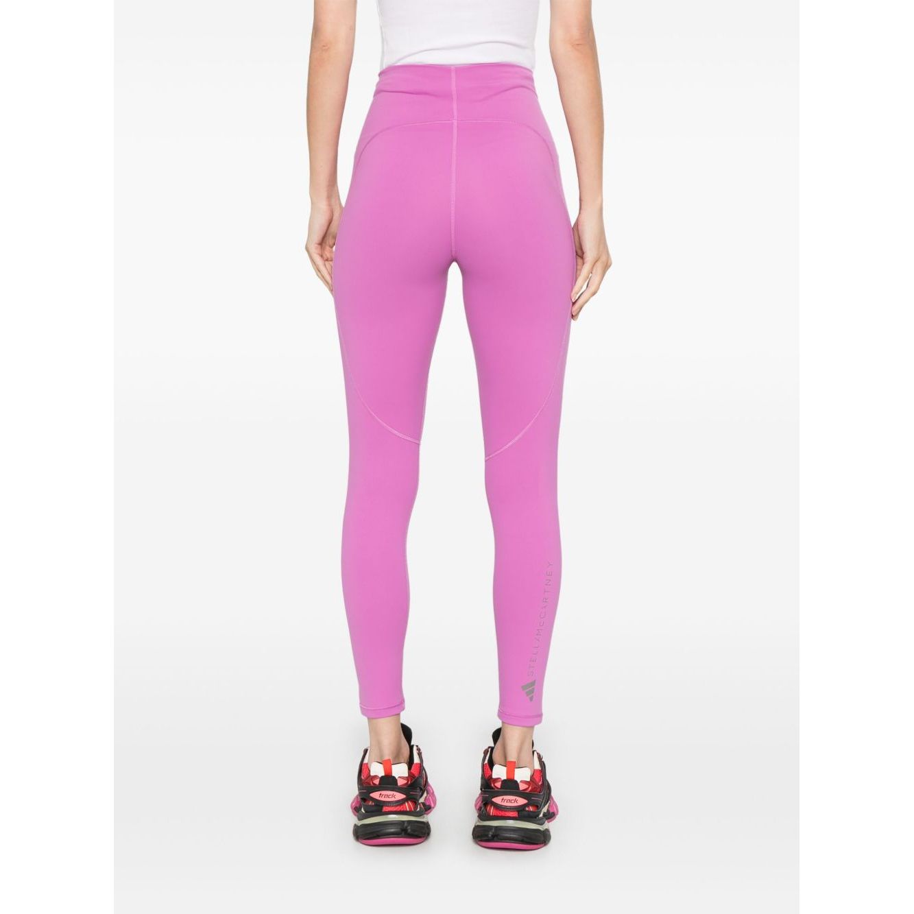 Back view of Adidas By Stella McCartney Trousers Purple, fuchsia pink with logo print at the leg, worn by a model.