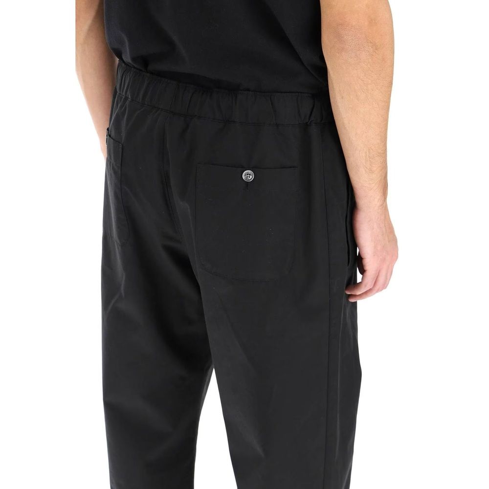 Model wearing Alexander McQueen Black Cotton Casual Pants showing back pockets and elastic waist detail.
