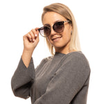 Lady wearing BALLY MOD. BY0043-K 6545B sunglasses, smiling and holding frames, official packaging available.