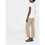 Model wearing Brunello Cucinelli Chain-trim round-neck t-shirt in white with beige pants and sandals, back view.