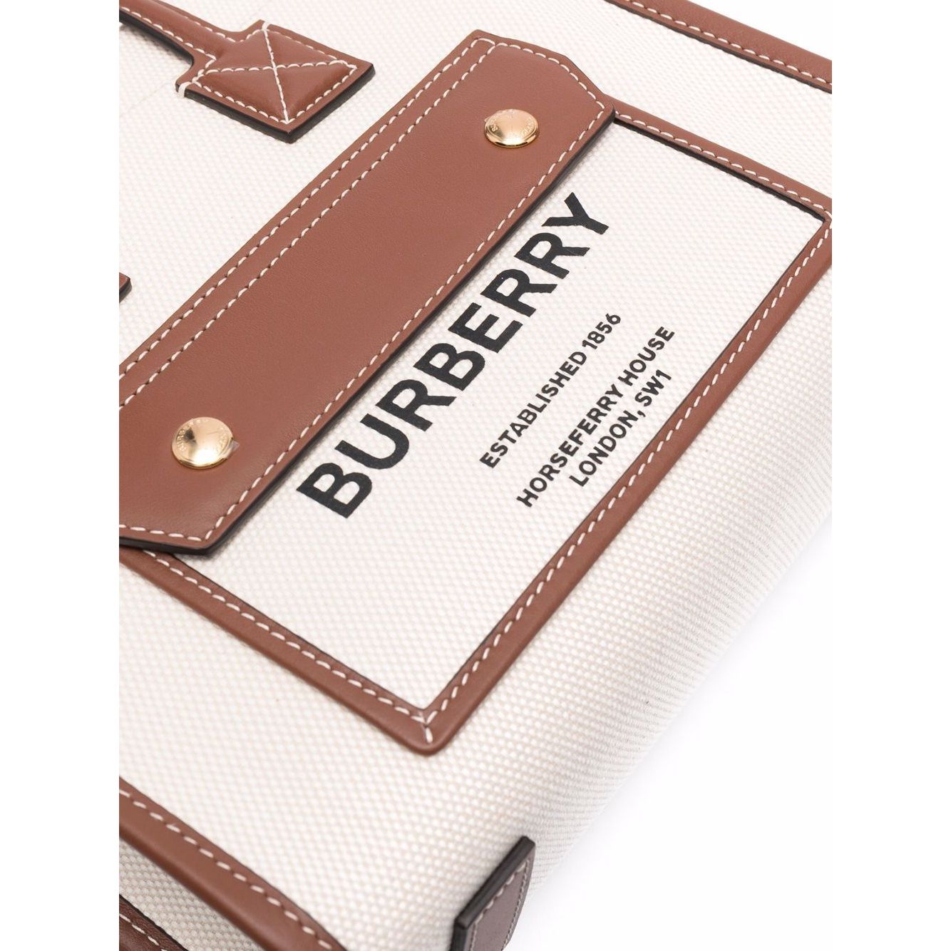 Close-up of cream/brown Burberry mini tote bag with logo print, leather trim, and gold-tone hardware.