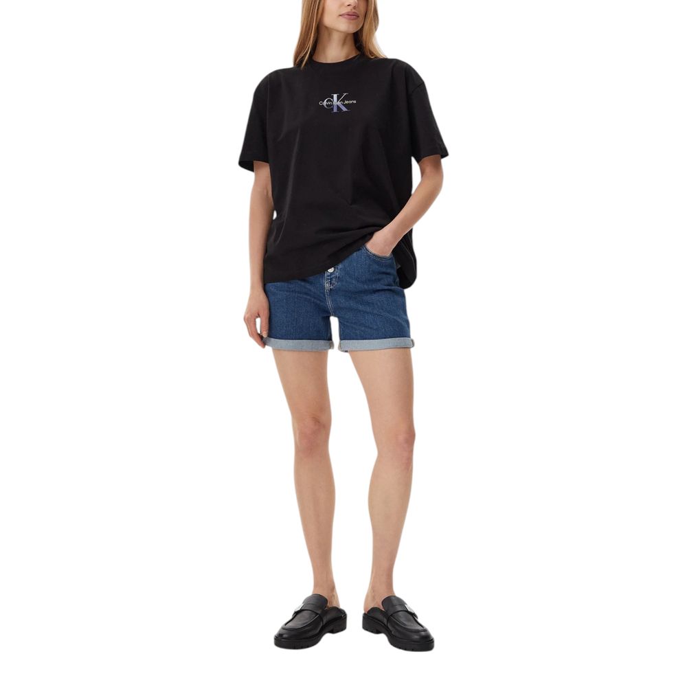 Woman wearing Calvin Klein Jeans Blue Cotton Shorts and black t-shirt standing with hands in pockets, showcasing casual summer style.