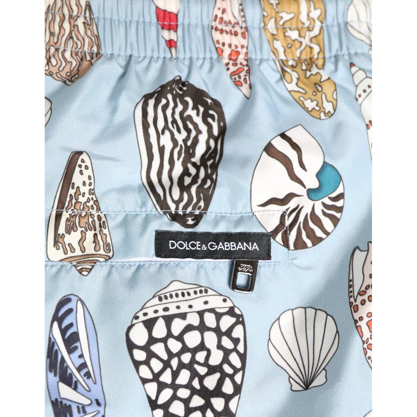 Dolce & Gabbana Blue Seashell Print Nylon Men Shorts Swimwear detail shot with vibrant seashell pattern and brand label.