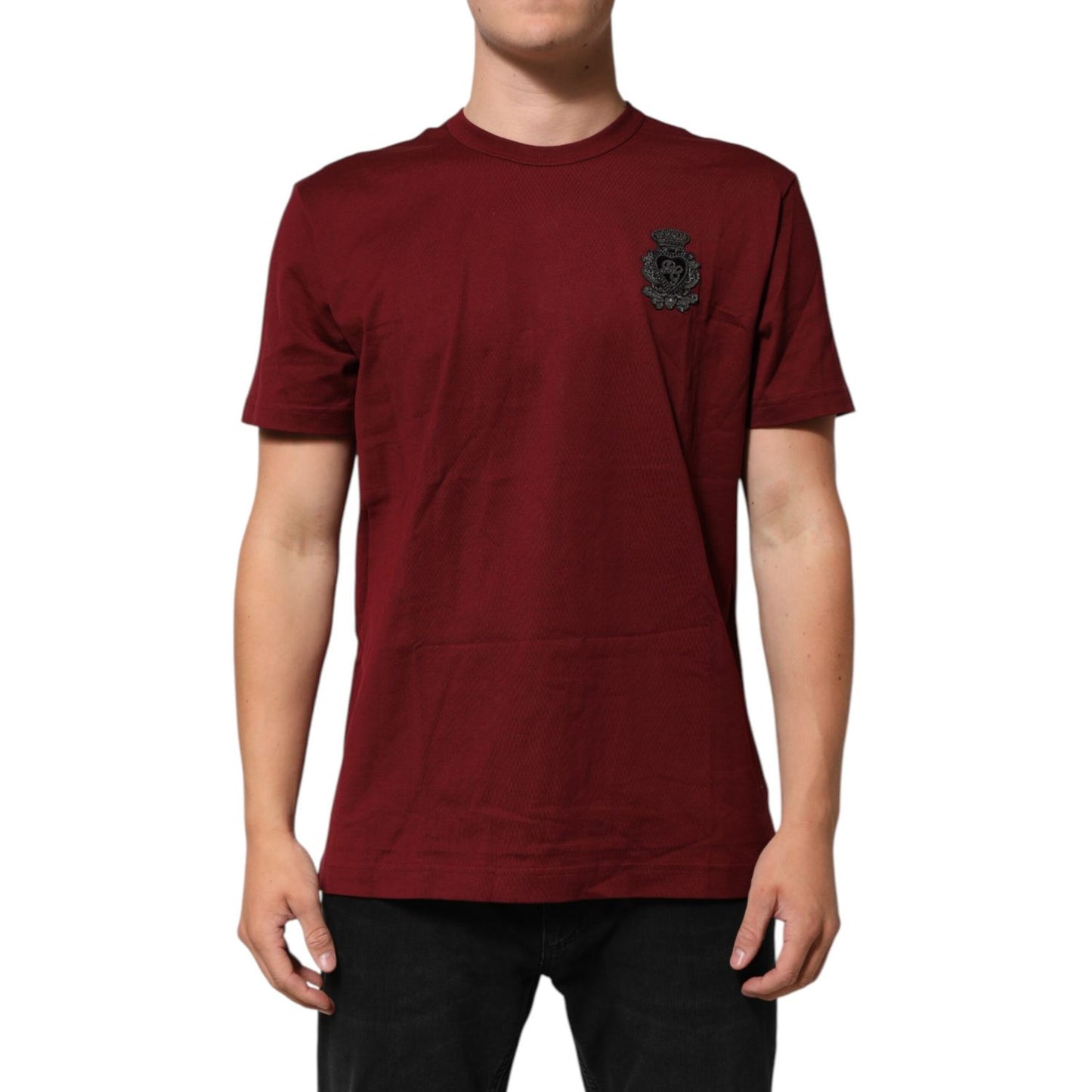 Man wearing Dolce & Gabbana Bordeaux Red Cotton Crest Logo Patch T-Shirt, showing embroidered crest logo, short sleeves, crew neck.