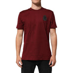 Man wearing Dolce & Gabbana Bordeaux Red Cotton Crest Logo Patch T-Shirt, showing embroidered crest logo, short sleeves, crew neck.