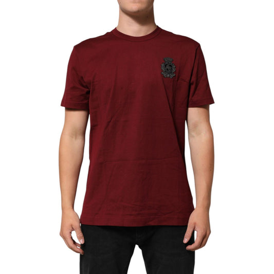 Man wearing Dolce & Gabbana Bordeaux Red Cotton Crest Logo Patch T-Shirt, showing embroidered crest logo, short sleeves, crew neck.