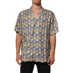 Man wearing Dolce & Gabbana Cream Cotton Silk Hawaii Scallop Shell Print Shirt with short sleeves, tropical design, sophisticated style.