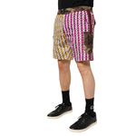 Model wearing Dolce & Gabbana Multicolor Playing Card Camouflage Shorts Swimwear with magenta, mustard, and camouflage details