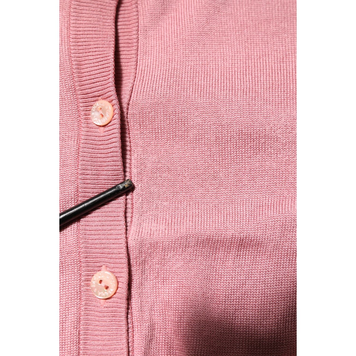 Close-up of Dolce & Gabbana Pink Silk Cropped Crew Neck Cardigan Sweater with button details and pulled threads.