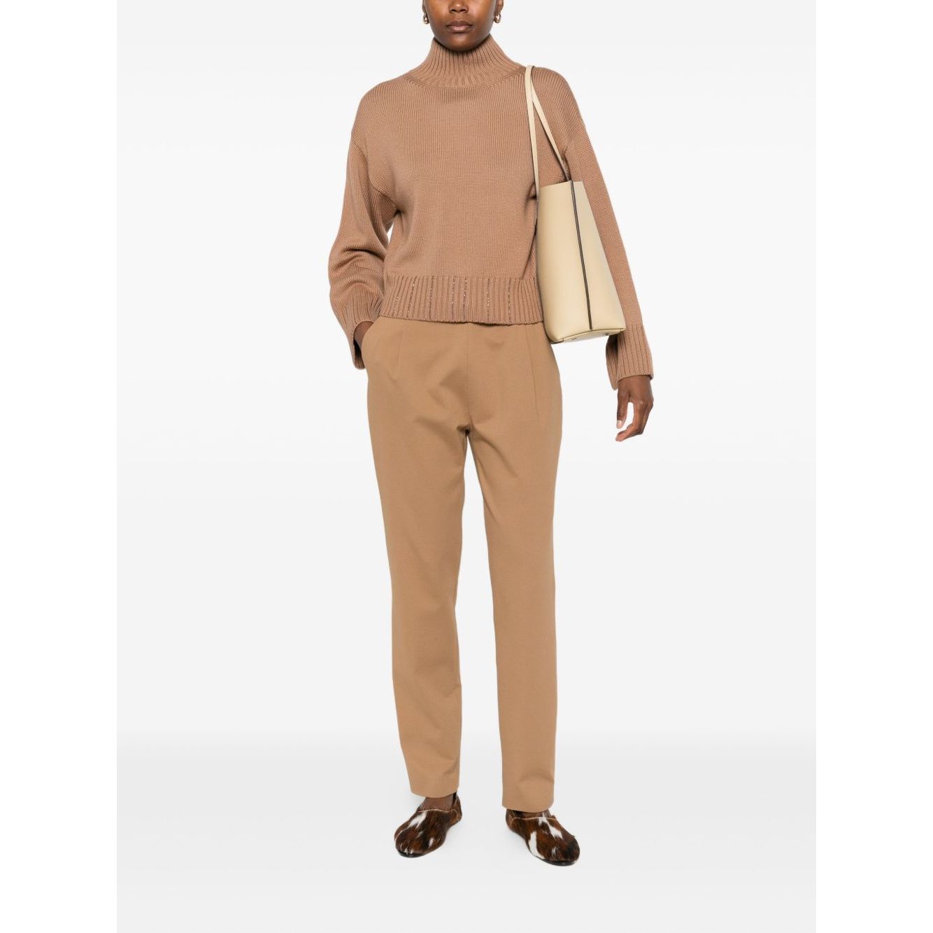 Woman wearing Fabiana Filippi Trousers Camel with brown pleated detailing and drawstring fastening, paired with knit sweater and tote bag.