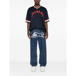 Man wearing ICECREAM Jeans Blue with Running Dog graphic and logo patch, featuring classic five-pocket design and straight hem.