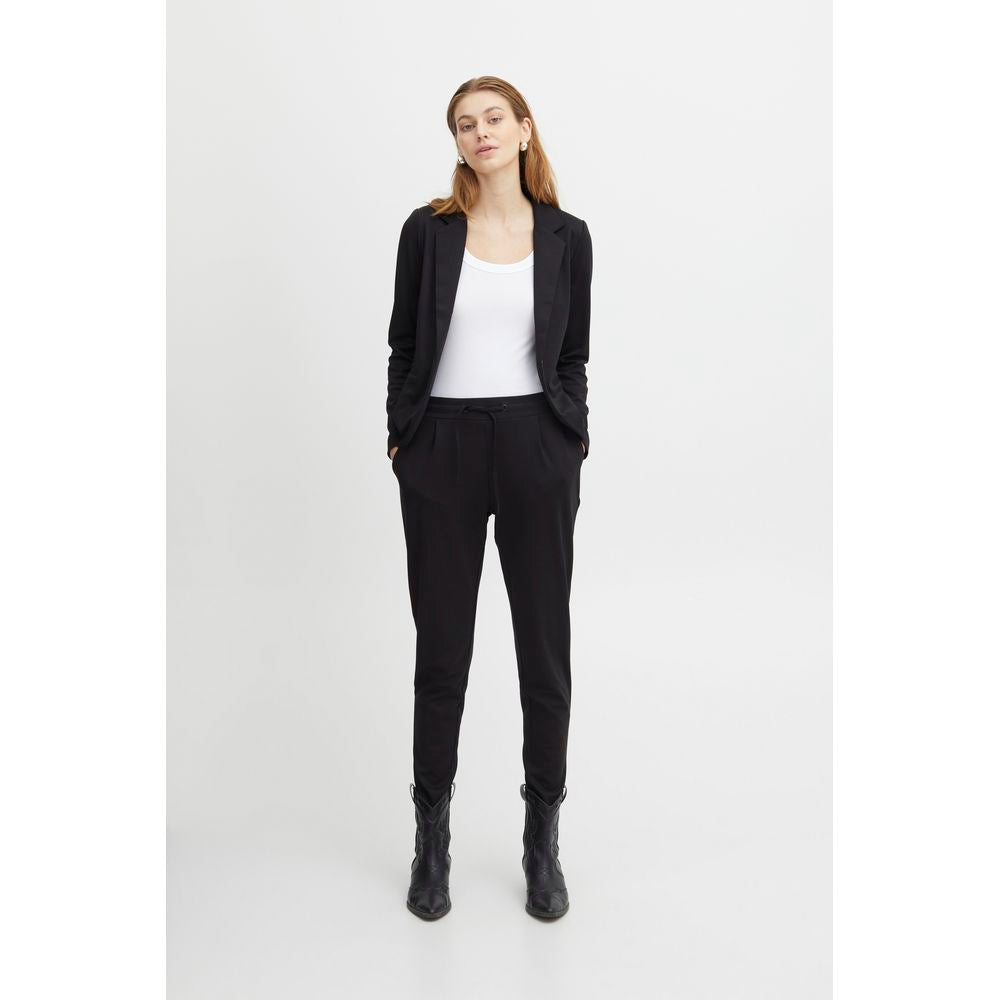 Woman wearing ICHI Black Polyester Pant with blazer, showcasing front pleats and elastic waist.