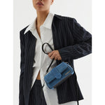 Model holding Jacquemus Denim Le Bambimou Petit Handbag with silver hardware and removable shoulder strap.