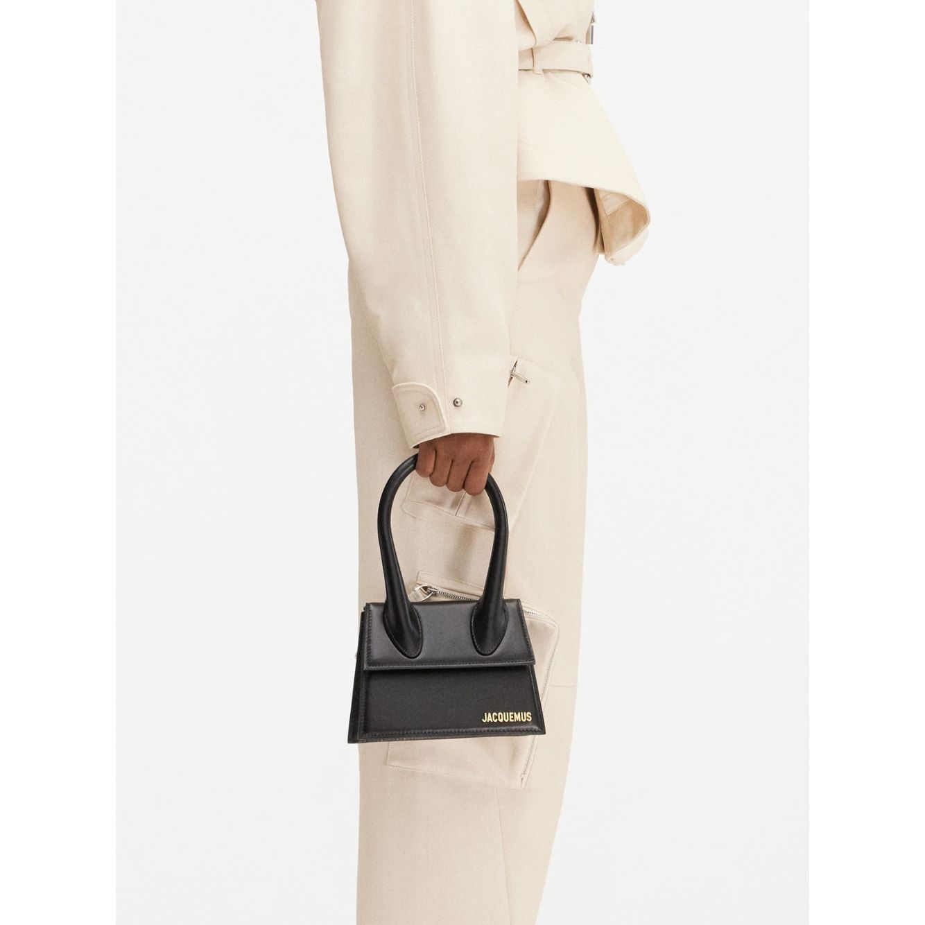 Jacquemus Le Chiquito Moyen Black Bag with gold hardware and removable strap, held by model, stylish Italian design, 18x13.5 cm.