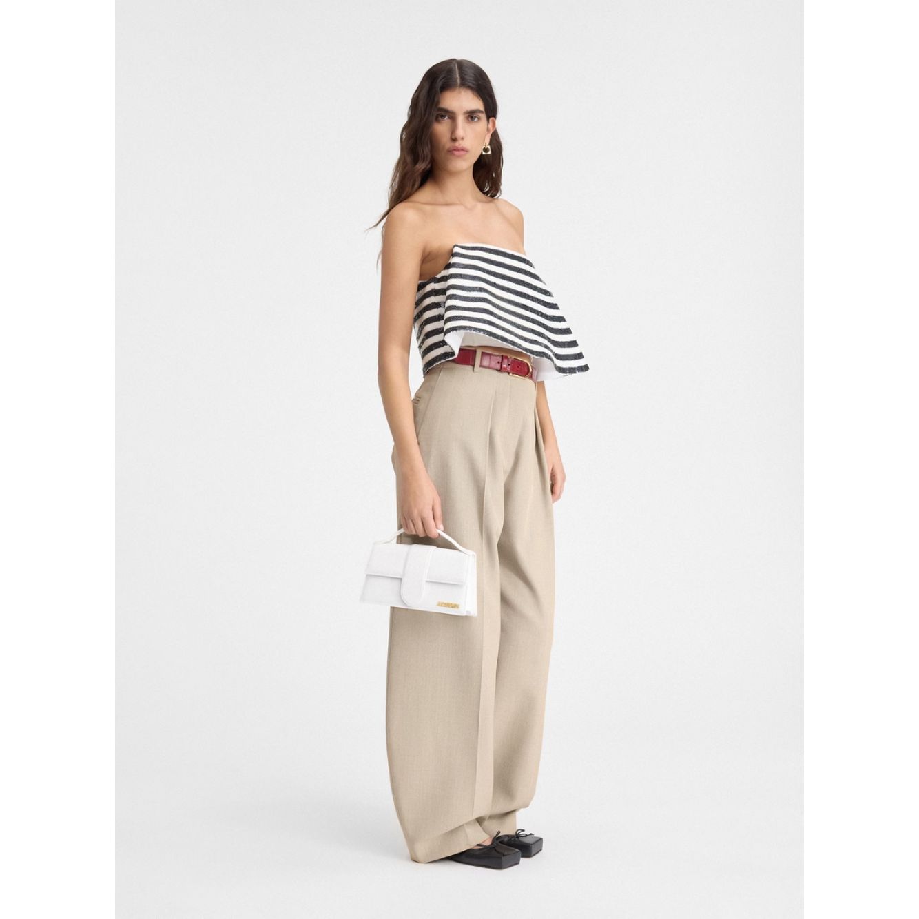 Model holding Jacquemus Le Grand Bambino White Bag with gold hardware, showcasing its elegant design and adjustable shoulder strap.