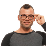 Person wearing black-rimmed glasses with short hair and a smile, modeling eyewear fashion on a white background.