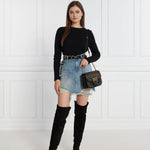Model wearing PINKO Black Wool Sweater paired with denim skirt and black boots, showcasing a chic outfit with metal logo detail.