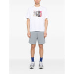 Model wearing Paul Smith T-shirts and Polos White, crew neck short sleeves with graphic print, styled with gray shorts and sneakers.
