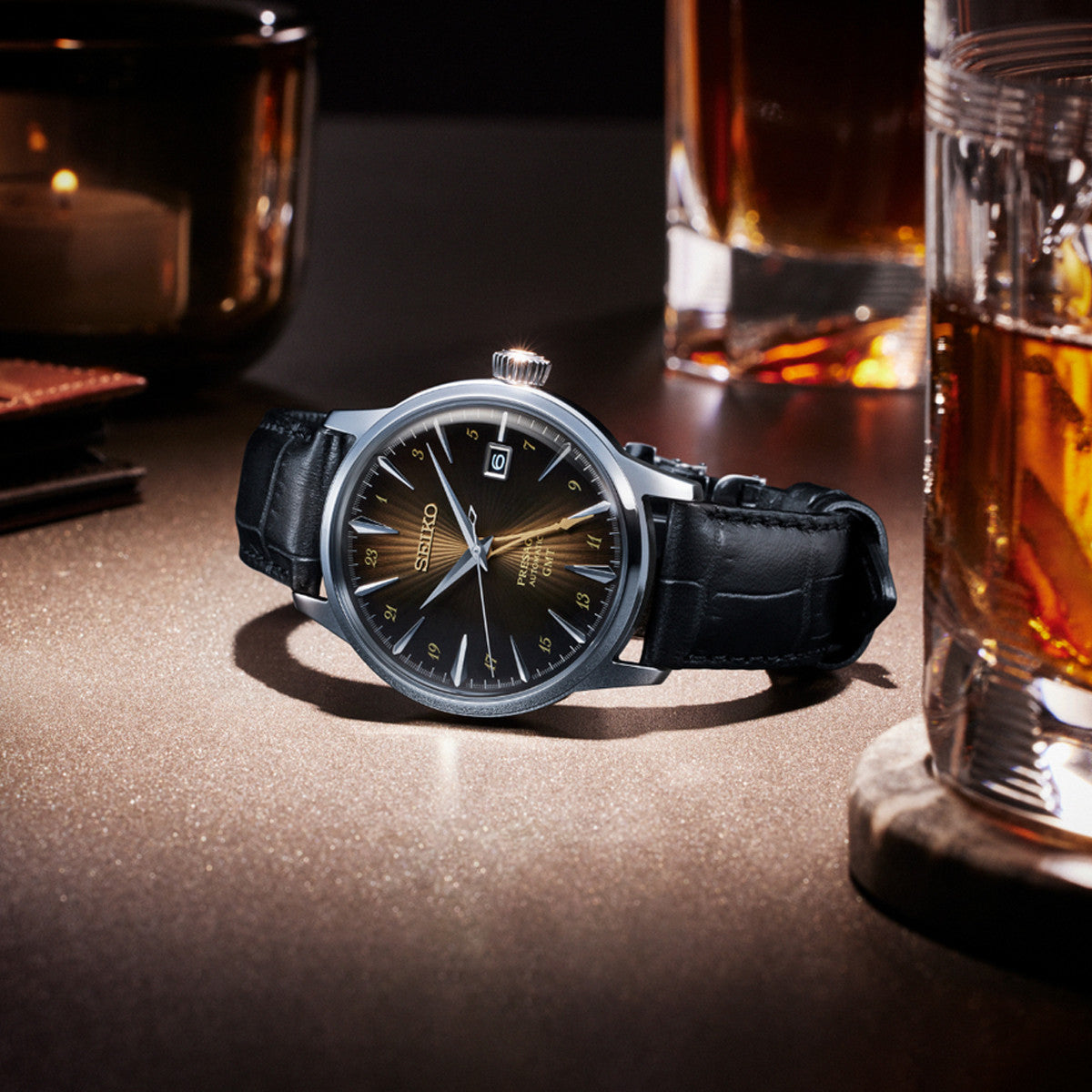SEIKO PRESAGE Mod. COCKTAIL AUTOMATIC - RUSTY NAIL wristwatch with leather strap, stainless steel case, and GMT function, on display table.