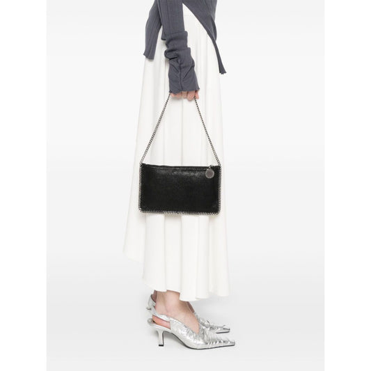 Woman holding a Stella McCartney Falabella clutch in black faux suede with chain-link strap and whipstitch trim.