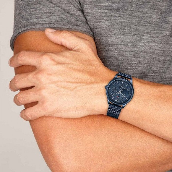 Person wearing TOMMY HILFIGER MOD. DAMON watch with blue mesh strap on wrist.