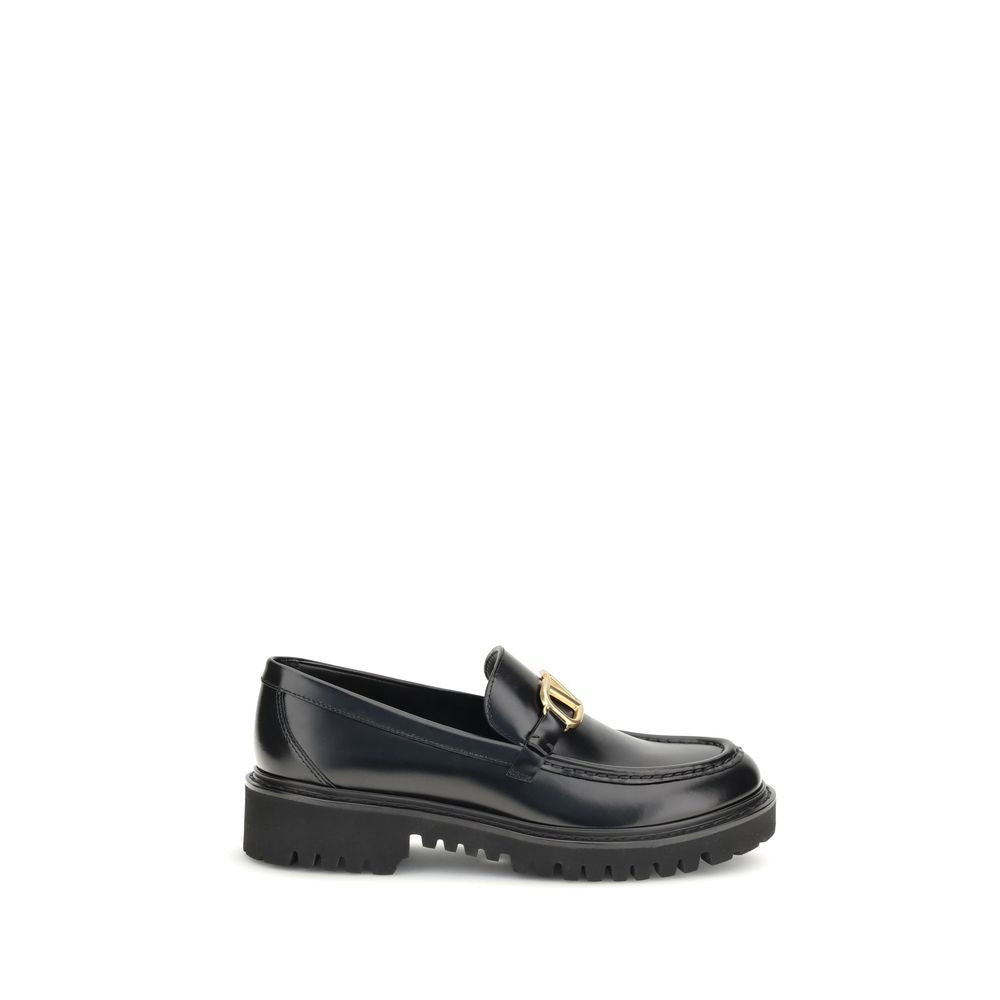 Valentino Garavani Black Leather Slip-On Loafers with brass VLogo detail on a rubber lug sole, side view.