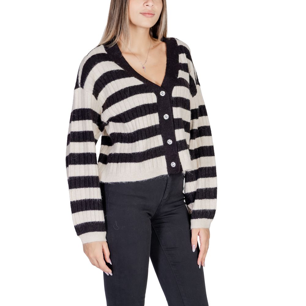 Woman wearing a black and white striped cardigan with button closures, styled with black pants, showcasing a casual fall/winter look.