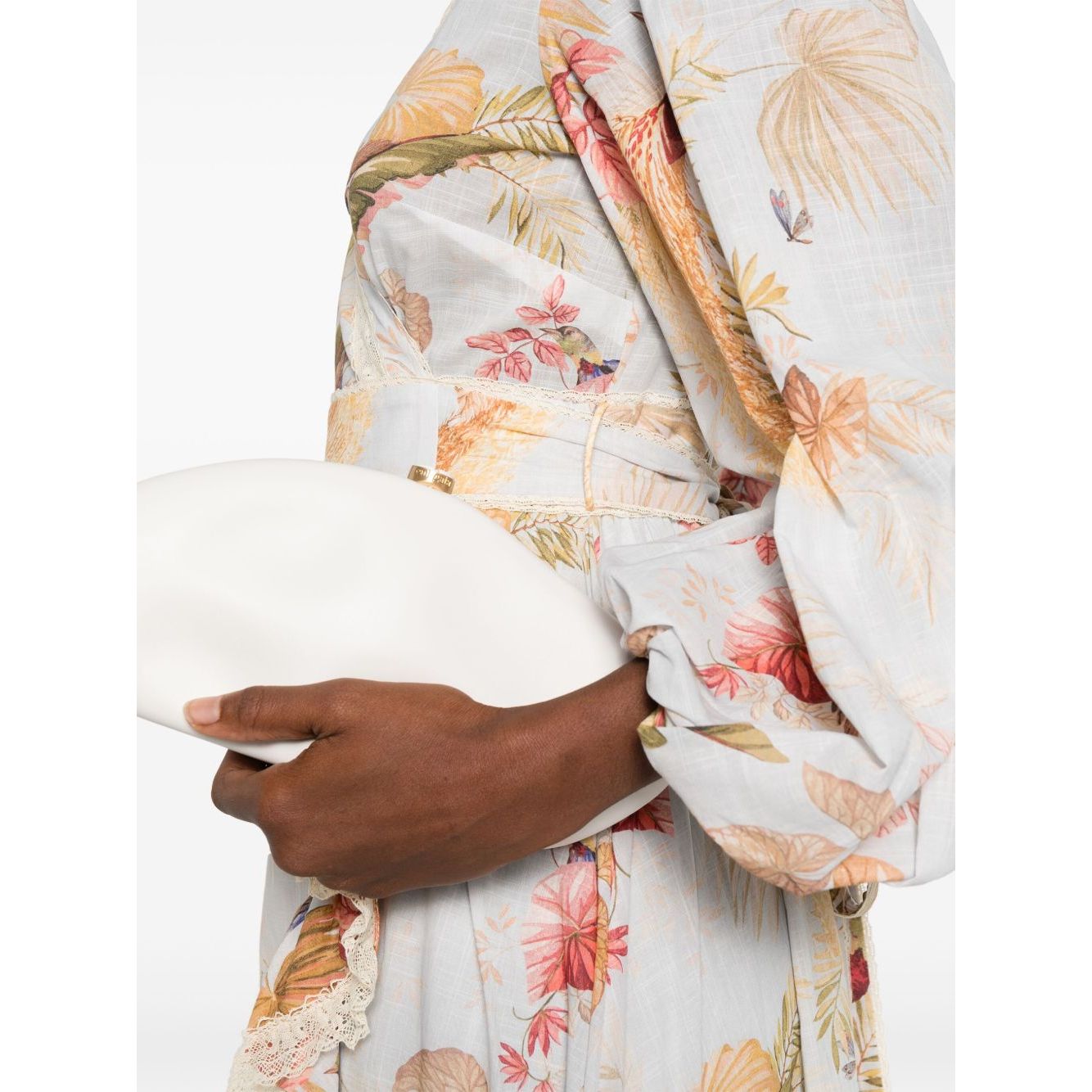 Close-up of Zimmermann Ascension Ruffled Midi Dress in light blue with floral print and lace trim, held by a model with a white clutch.